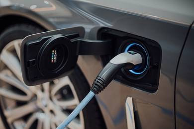 Close-up photograph of a charger plugged into an electric vehicle. 