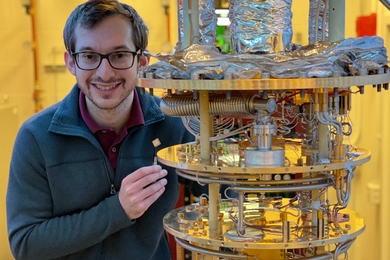 Photo of Daniel Rodan-Legrain standing next to a high-tech assemblage of tubes and disks