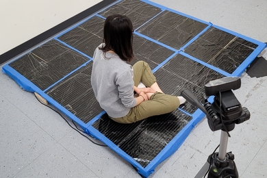 Photo of a person sitting cross-legged on the tactile carpet 