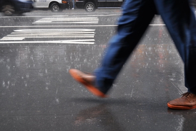 Motion-blurred photo of someone’s legs walking on a rainy street.