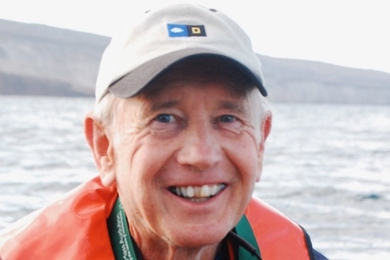 Portrait photo of Fred Frey wearing a life jacket and smiling with a water scene behind him