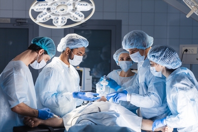 Photo of a team of surgeons and an anesthesiologist gathered around a patient on an operating table