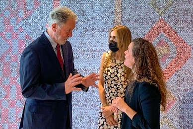 MIT Professor Sarah Williams discusses research with two World Food Program board members in front of a multi-colored tapestry. 
