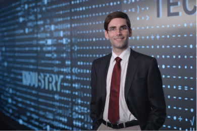 Tomás Palacios stands in front of a large blue screen which reads "Industry”.
