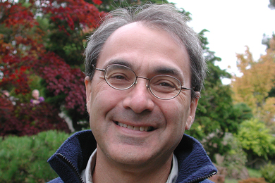 Headshot of Alfred Spector standing before trees with red, yellow, and green leaves