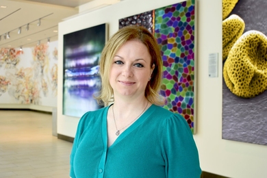 Nicole Henning standing in front of some large scientific images displayed in a hallway