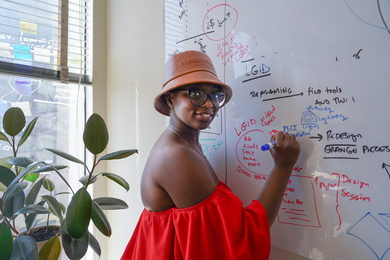 Mariama N'Diaye looks at the camera while writing on a whiteboard, in her MIT office. 