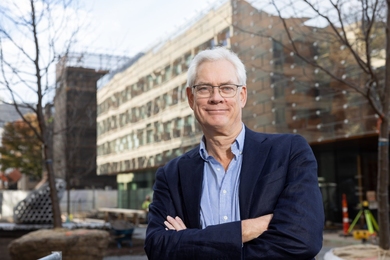 Robert van der Hilst poses for a photo in front of a blurred new building on the MIT campus.