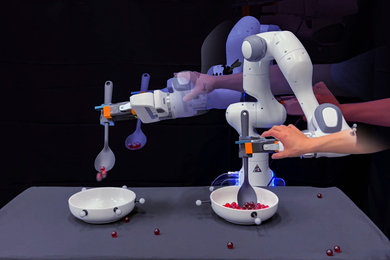 About five photos of a robotic experiment are collaged together. A robotic arm uses a spoon to pick up red marbles and place in a bowl. A human hand pushes and pulls the robotic hand. Marbles are scattered on the table and are also being poured into the new bowl.