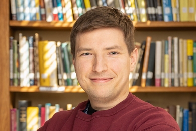 Headhshot of Mikhail Ivanov with a bookcase behind him