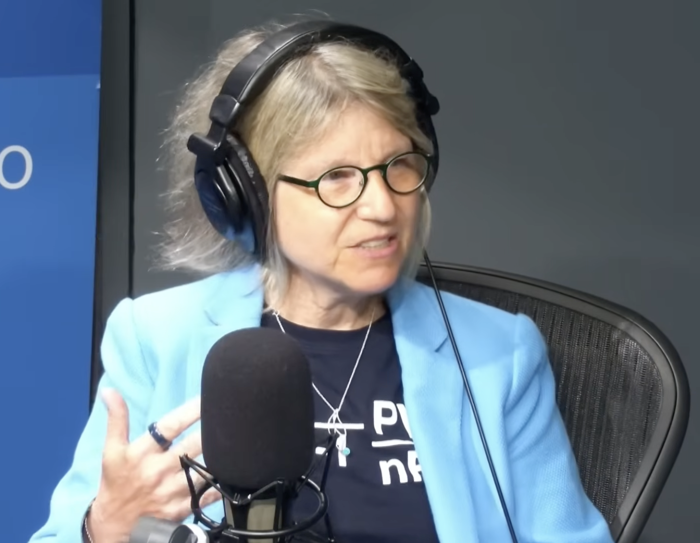 President Sally Kornbluth wearing headphones and speaking into a microphone during an interview with Boston Public Radio.