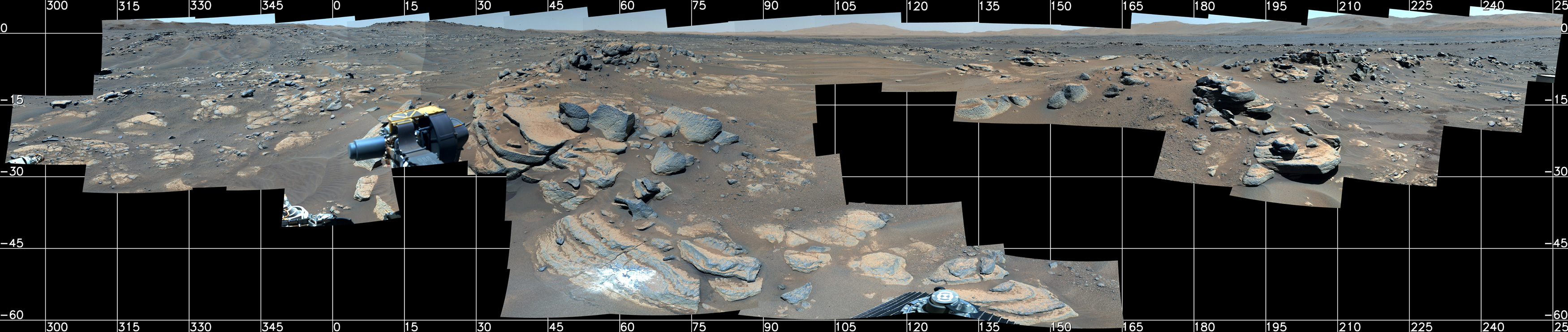 Against a dark grid with location points, a mosaic of photos is collaged together showing the rocky surface of mars. Some rocks create strong shadows and have a bluish-grey color, while most of the surface is tan.