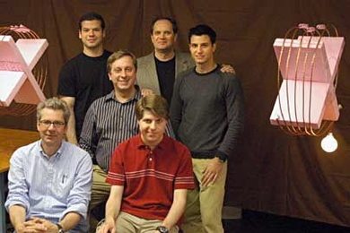 Wireless power transfer over two-meter distance, from the coil on the left to the coil on the right, where it powers a 60W light bulb. Members of the team that performed the experiment are obstructing the direct line of sight between the coils; front row: Peter Fisher (left) and Robert Moffatt; second row: Marin Soljacic; third row: Andre Kurs (left), John Joannopoulos and Aristeidis Karalis.