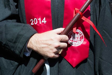 Close-up of graduating student holding a wooden stick with ribbon