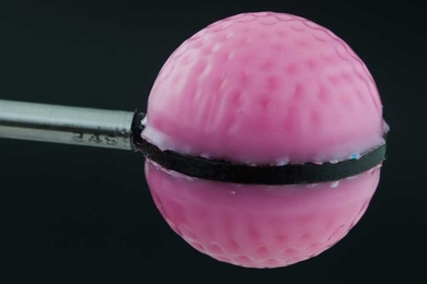 Pink golf ball attached to metal stick, split in half horizontally