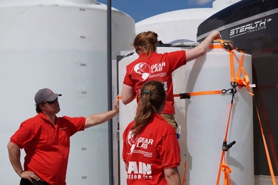 Professor of mechanical engineering Amos Winter (left) and graduate students Natasha Wright (on ladder) and Georgia Van de Zande assemble their desalination system a day before the USAID Desal Prize competition, which they won.
