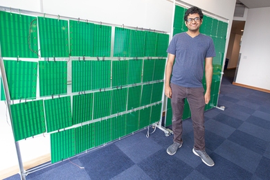 Venkat Arun of MIT stands in front of the prototype of RFocus, a software-controlled “smart surface” that uses more than 3,000 antennas to maximize the strength of the signal at the receiver.