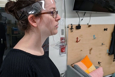 Robyn Goodner, who serves as a maker technical specialist for Project Manus, models the face shield design in the Metropolis Makerspace.