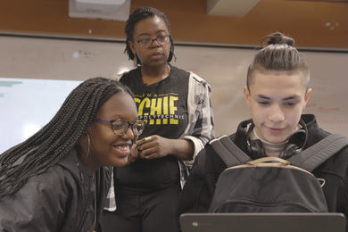 Photo of three young people looking at a laptop