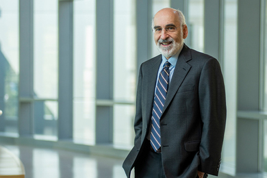 John Sterman stands in front of a bank of windows