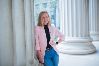 Kaylee Cunningham leaning against a pillar with one hand on her hip, outdoors.