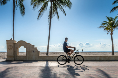 Person on bike near ocean on a sunny day.