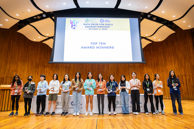 On stage, a lineup of 14 girls display their trophies