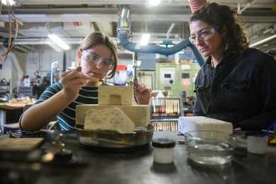 Rhea Vedro supervises a student working with metalsmithing tools