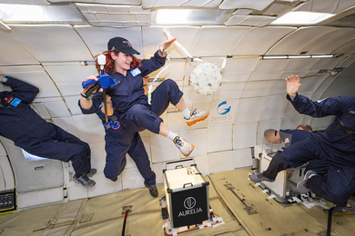 Five people in blue suits float in zero-gravity.