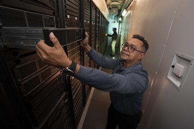 Antonio Rosa slides server equipment from a huge rack inside of a data center. 