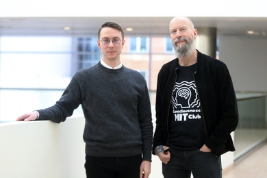 Matthias Michel and Earl Miller pose together on the balcony of an atrium