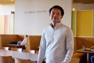Patrick Yeung poses, standing in the MIT Sloan Cafe