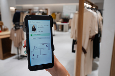 A person looking at the Cartesian Systems app while in a clothing store