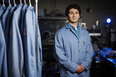 Hugh Smith stands in the lab next to lab coats.