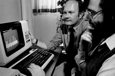 Grayscale photo of Roger Mark and George Moody looking at an early computer's small screen