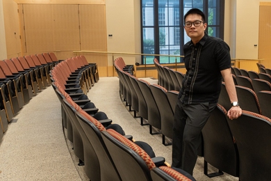 Lyonel Tanganco leans against a seat back in a large, empty classroom