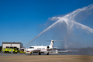 Water from two high-pressure hoses forms an arc over a Gulfstream aircraft.