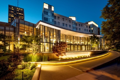 MIT Sloan School of Management building is brightly lit up and pictured at dusk.