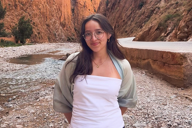Isabel Duran stands in a sunlit canyon, on the margins of a riverbed