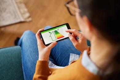 Photo of a phone screen depicting a home efficiency rating, taken over the shoulder of the person using it