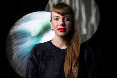 Amy Karle stands in front of a black background and two overlapping circular projections.