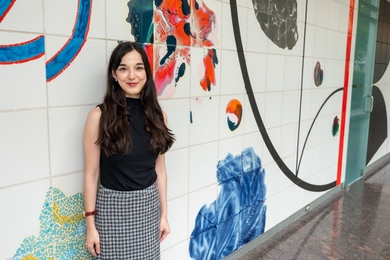 Marina Milea poses, standing, in a colorfully painted hallway