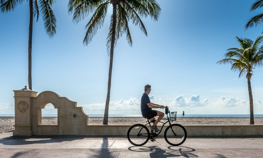 Person on bike near ocean on a sunny day.