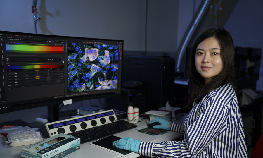 Xiao Wang portrait, seated at a computer showing lots of data.