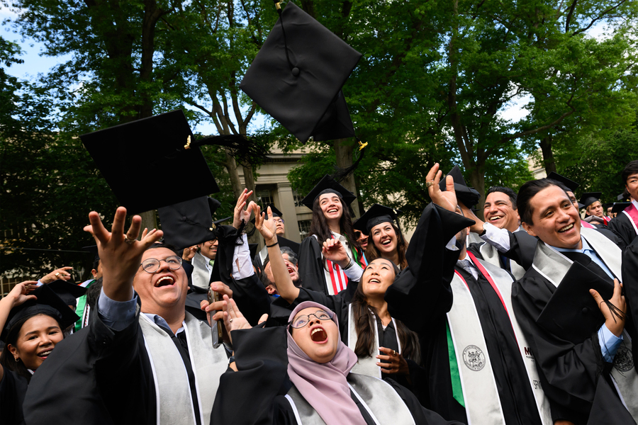 Graduates in caps and gowns celebrate, throwing caps in the air