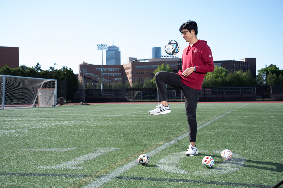 Henry Wang knees a soccer ball on the field.
