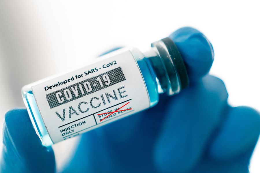 A gloved hand holds bottle of vaccine dosage 