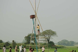 Members of the Harvey Lab and local workers from a nearby village in Bangladesh install a 20-plus-foot tower in a rice field. The red cage on the tower housed a waterproof box containing the datalogger and battery that powered, controlled and recorded data collected by 18 hydrologic sensors installed by Rebecca Neumann (in the green hat).
