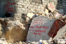 On rubble from the aftermath of the Haiti earthquake, a merchant has inscribed "Notice: The artist is not dead. Call 3907-9920 for your shirt-printing jobs."