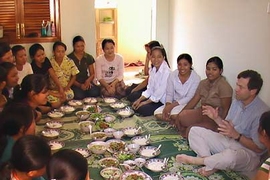 Alan Lightman, at right, shares a meal with Cambodian students. The Harpswell Foundation, which he and his wife founded, built a dormitory for the women so they could attend college in Phnom Penh.